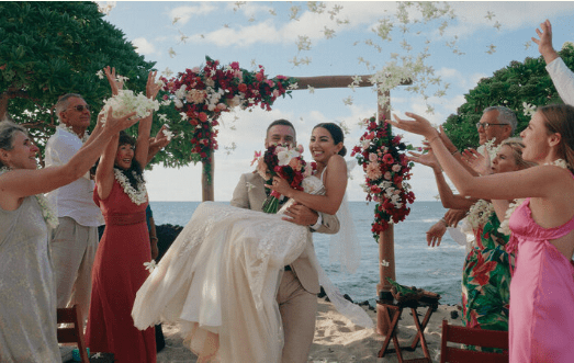 Newlywed couple celebrating after their wedding ceremony at Four Seasons Resort Hualalai, smiling and embracing outdoors.