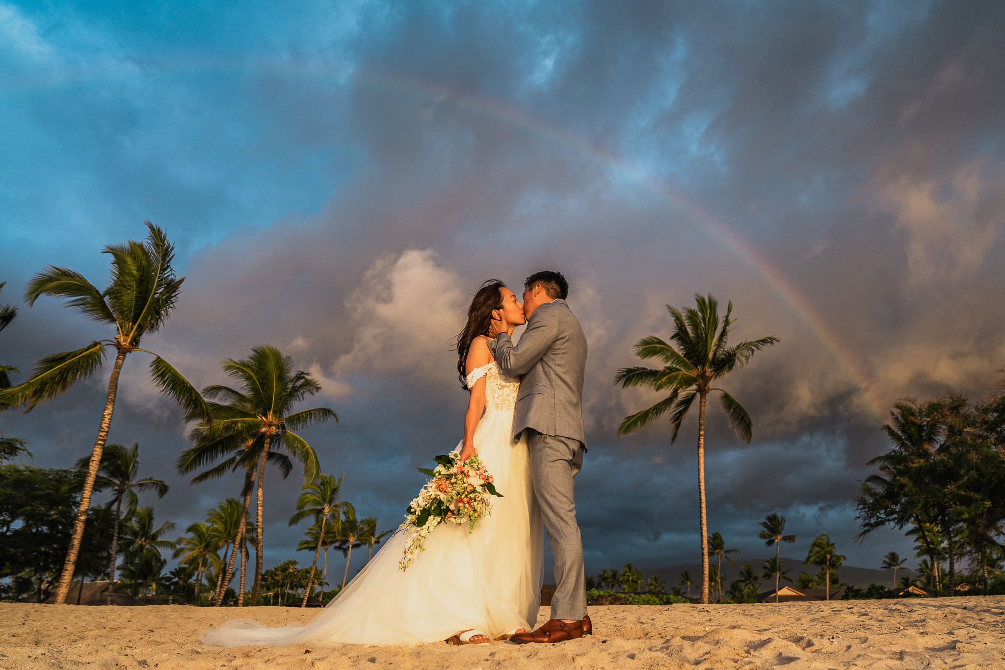 Couple embracing on white sand beach in kona
