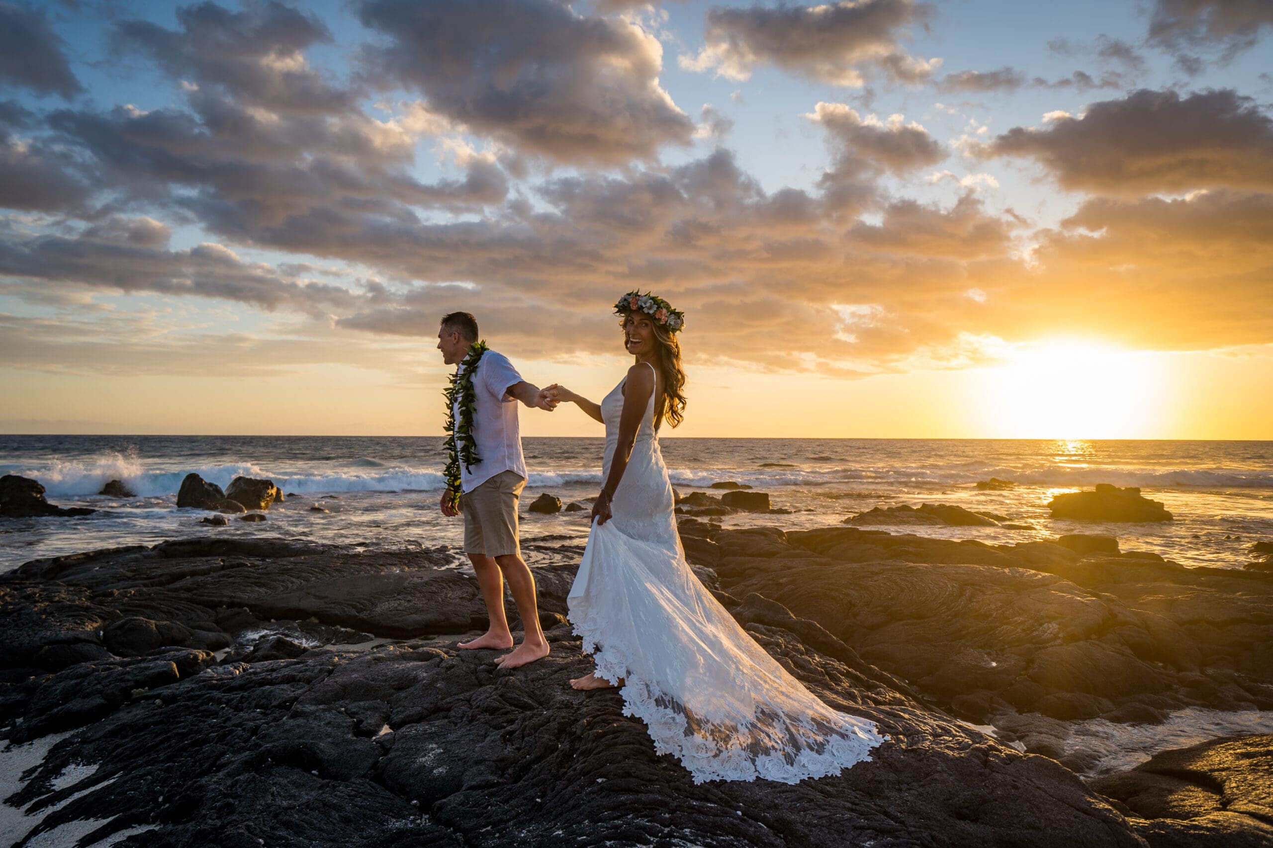 Couple eloping at sunset on lava rock cliffs, Big Island Hawaii wedding photo