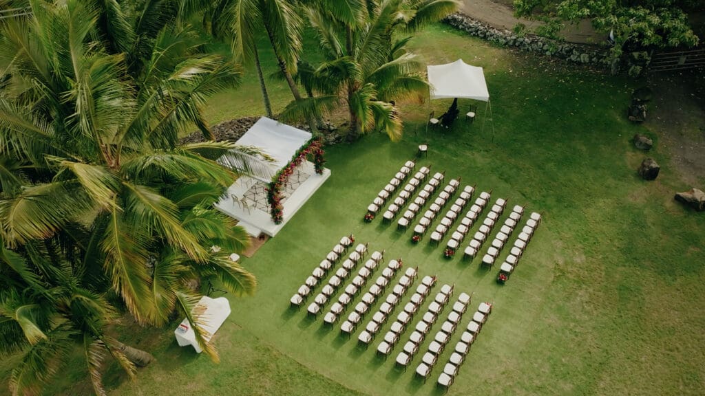 Aerial view of an Indian wedding ceremony at Paliku Gardens on Oahu, surrounded by dramatic mountain and tropical landscapes