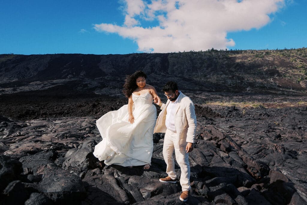 Couple walking hand in hand on ancient lava flows at Hawai'i Volcanoes National Park, Big Island Hawaii wedding photography

