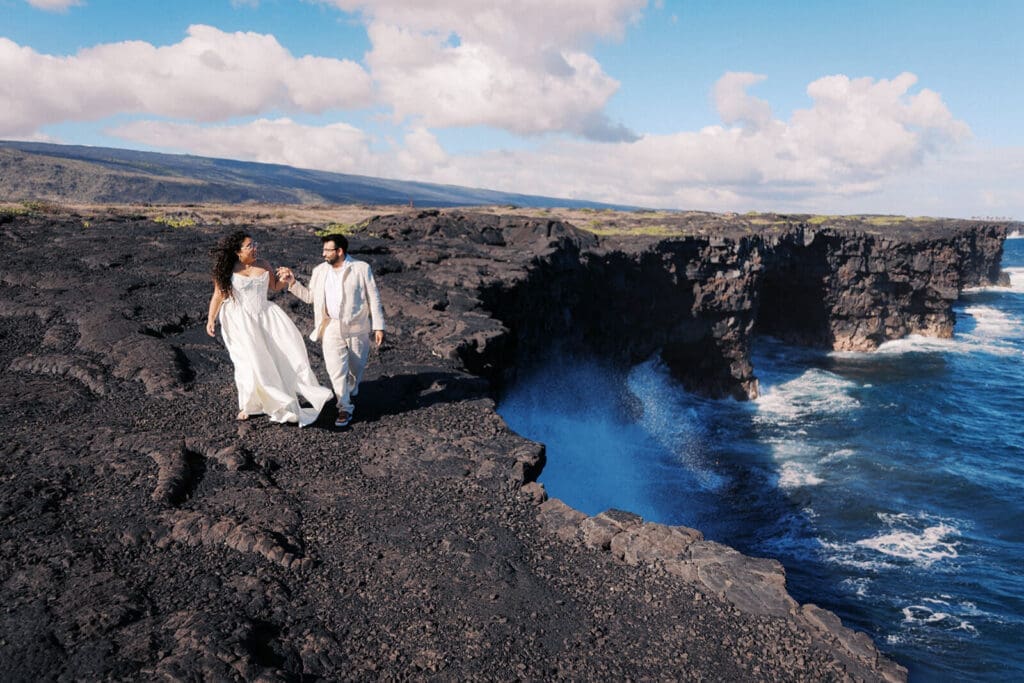 Couple walking along dramatic cliffside with ocean views at Hawai'i Volcanoes National Park, Big Island
