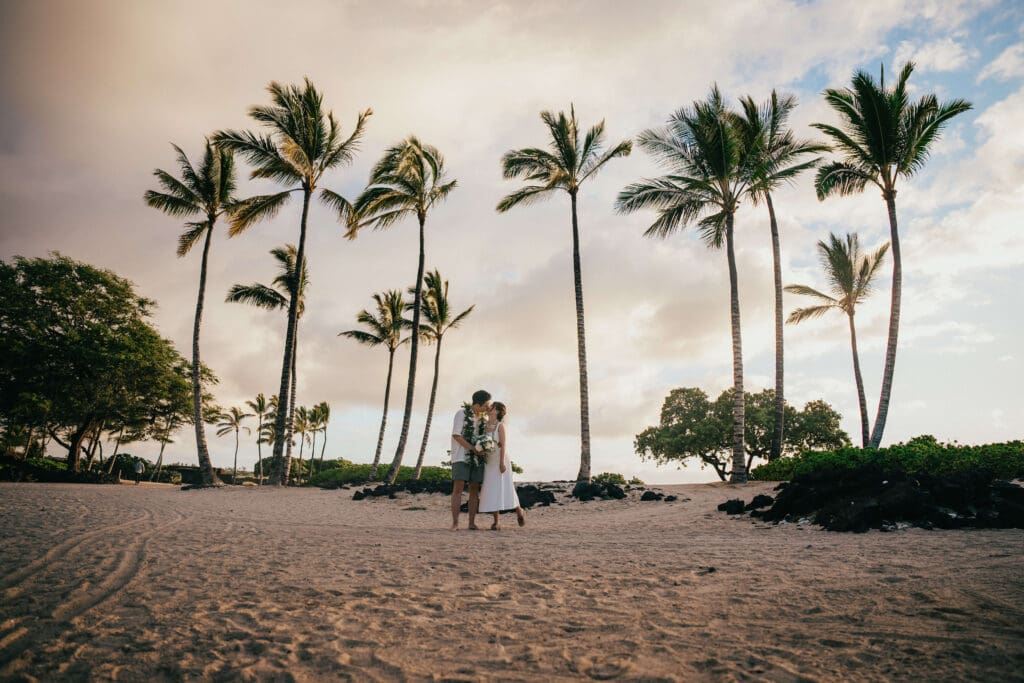 Couple kissing under palm trees at sunset, Kikaua Point Park, Kona Hawaii
