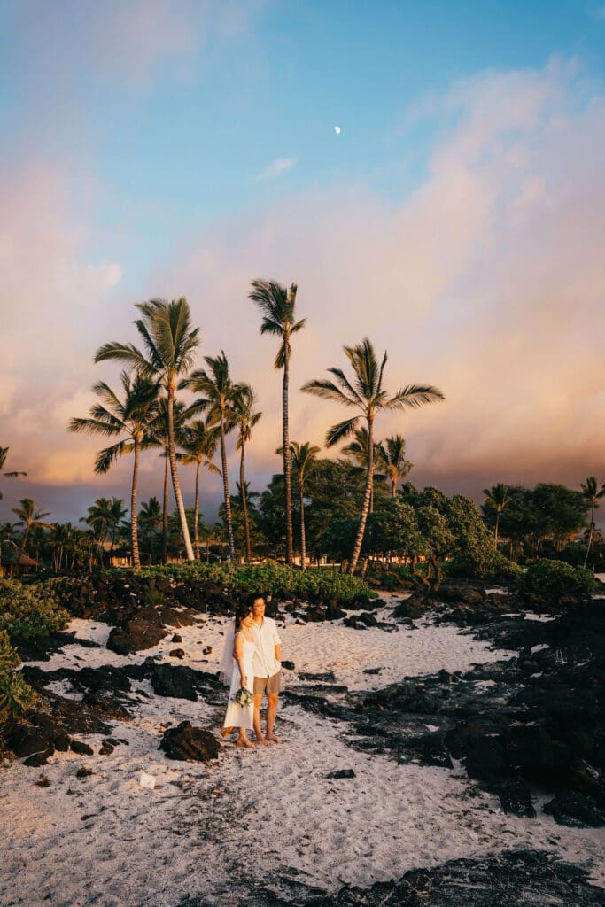 Couple at sunset on the beach with lava rocks at Kikaua Point Park, Kona Hawaii wedding photography