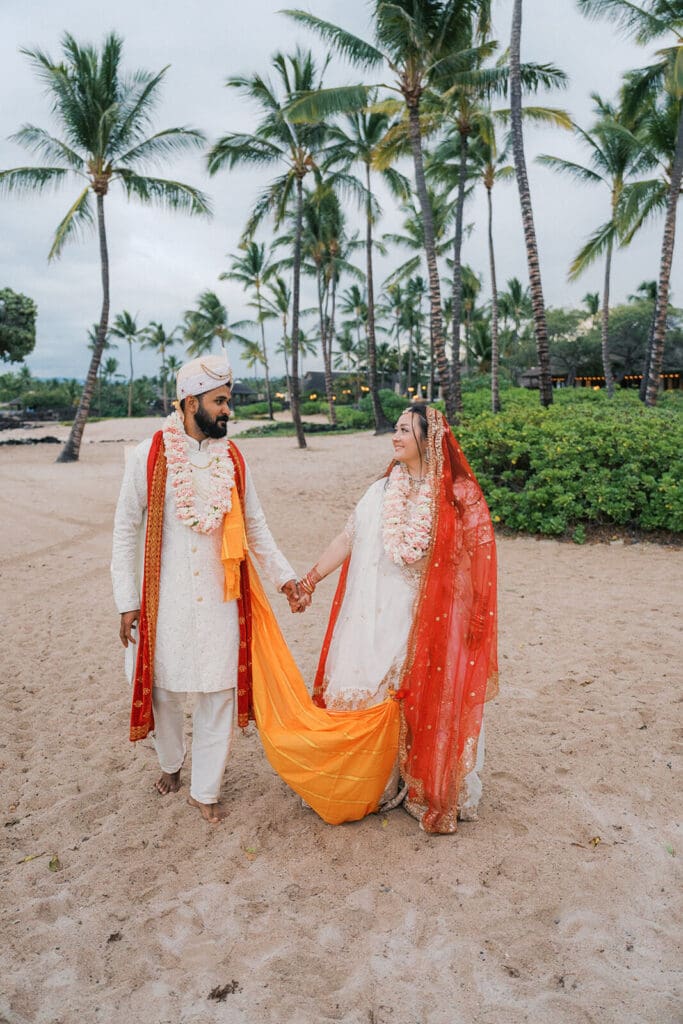 Couple walking after Hindu Indian wedding ceremony at Kikaua Point Park, Big Island Hawaii