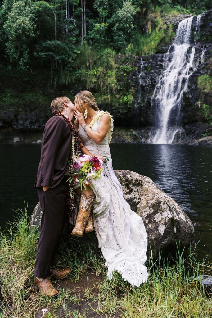 Couple sitting on a rock kissing at Kulaniapia Falls, Big Island Hawaii