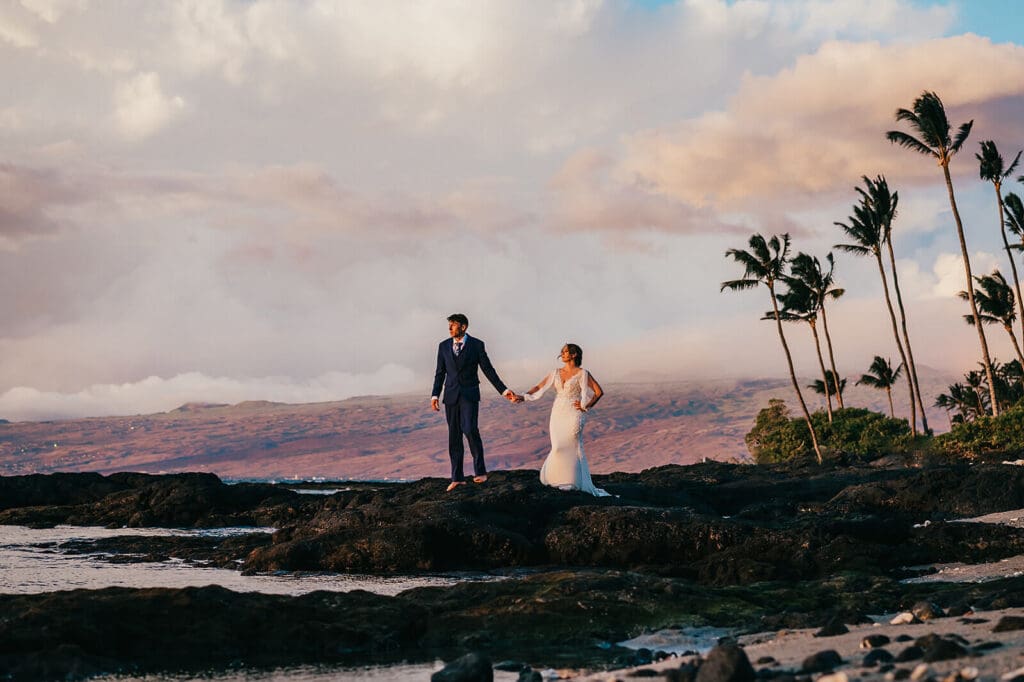 Couple walking on lava rocks at sunset at Mauna Lani, Big Island Hawaii wedding photography