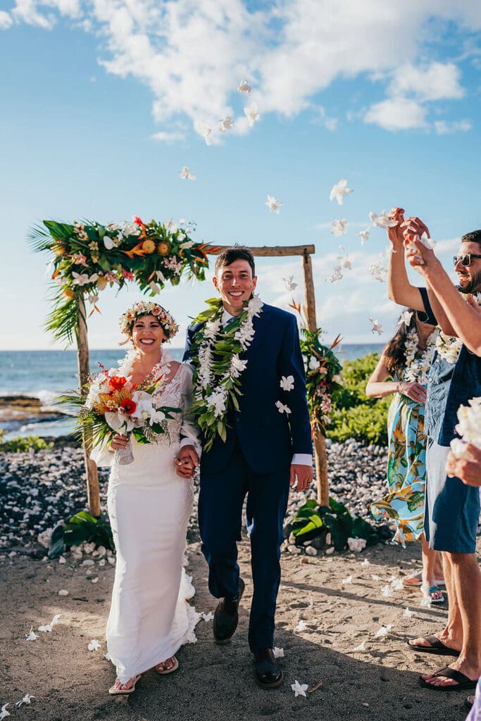 Couple celebrating wedding ceremony with flowers being thrown at Mauna Lani Resort, Big Island Hawaii