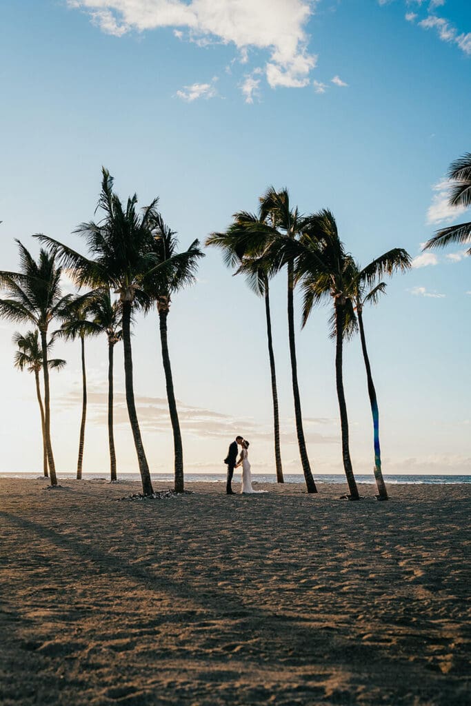 Couple kissing under palm trees at Mauna Lani, Big Island Hawaii wedding photography