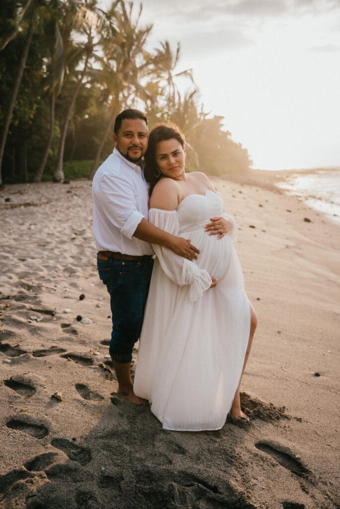 Maternity photo of couple holding baby bump at Ke'ei Beach, Big Island Hawaii