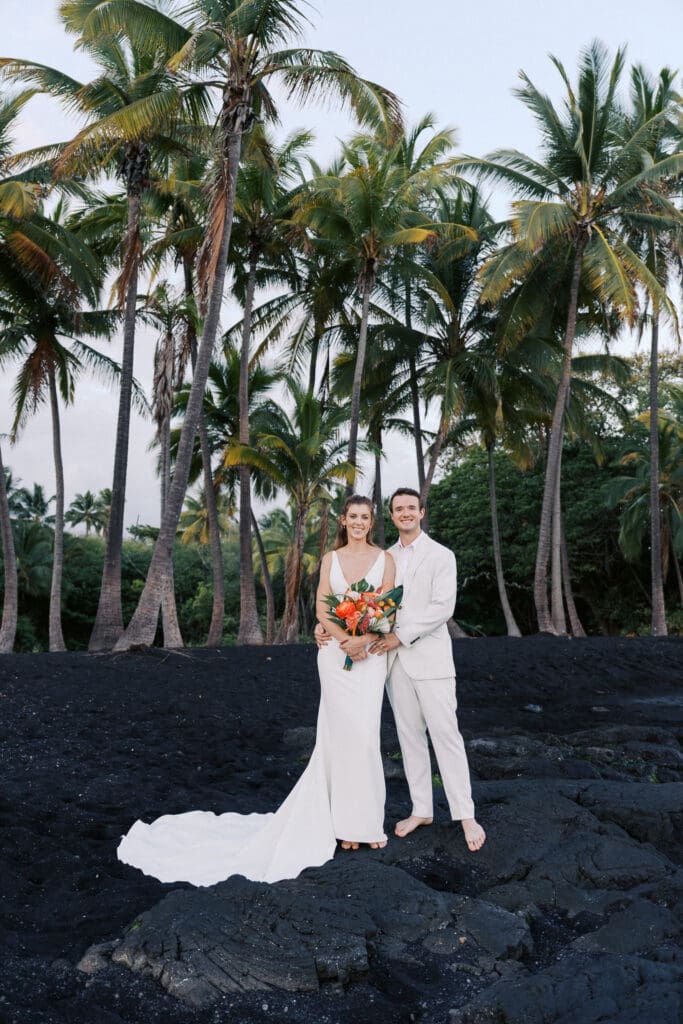 Couple posing in front of palm trees at Punalu'u Black Sand Beach, Hawaii wedding photography
