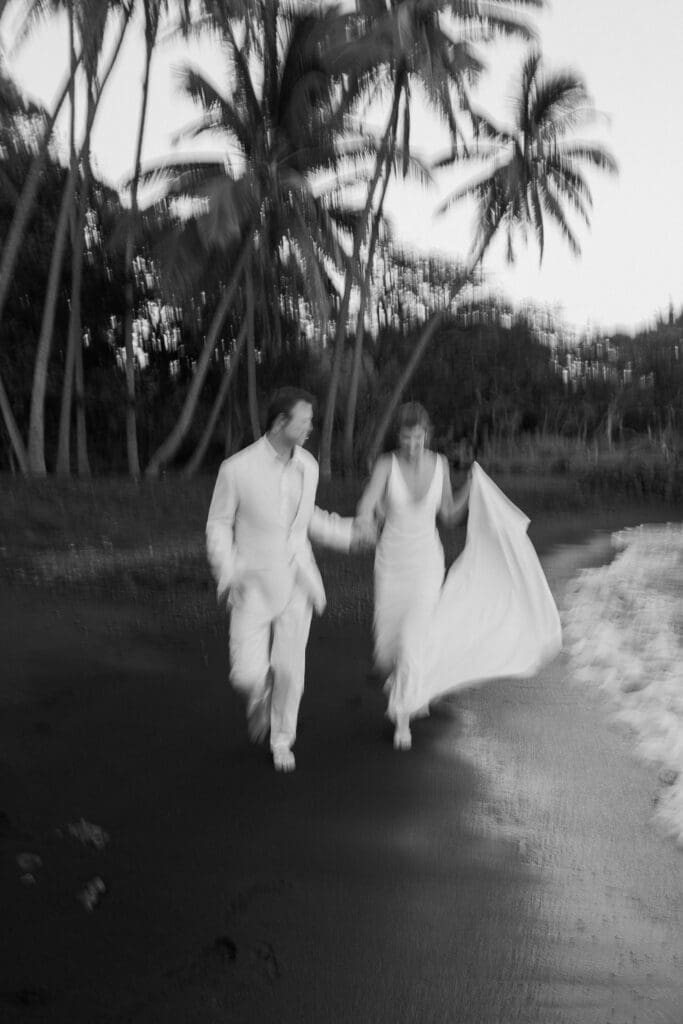 Black and white photo of couple running on Punalu'u Black Sand Beach, Big Island Hawaii
