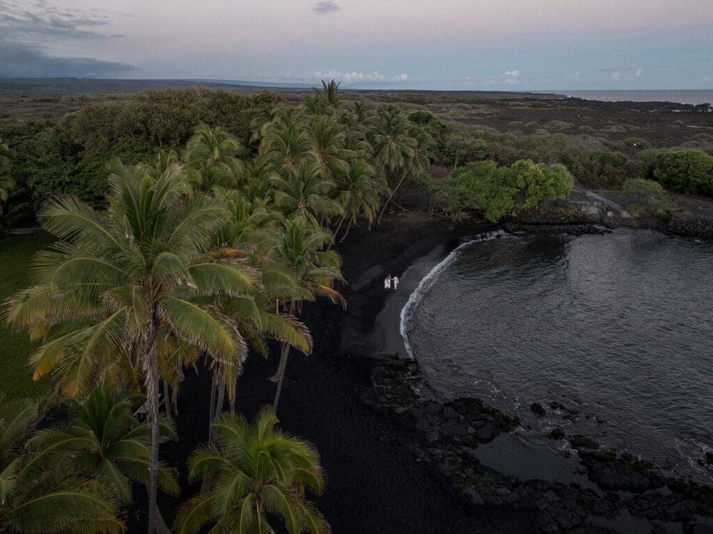 Drone shot of couple walking on Punalu'u Black Sand Beach, Big Island Hawaii