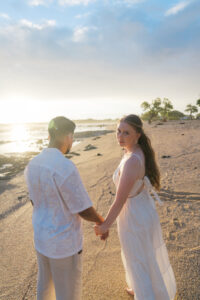 Bride and groom holding hands on the shoreline during a Big Island couples session