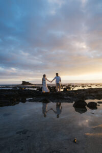 Couple embracing on black lava rocks at Old Kona Airport Beach